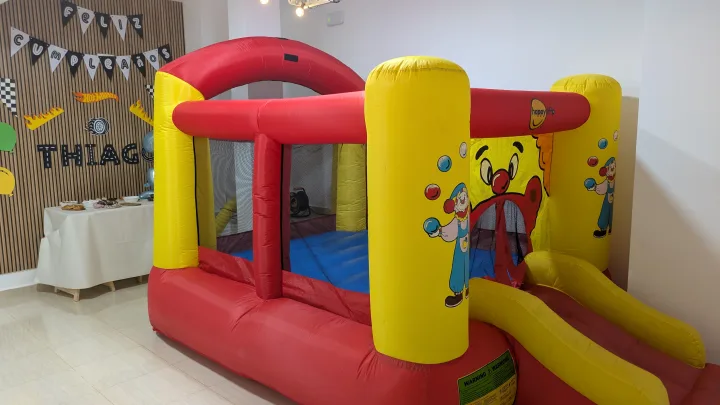 Castillo hinchable rojo y amarillo con tobogán en el interior del local.