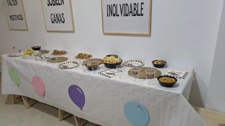 Detalle de la mesa preparada con aperitivos, platos y vasos para una celebración.