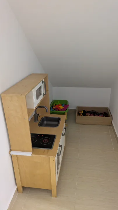 Cocinita infantil de madera y cajas de juguetes en un rincón del local.