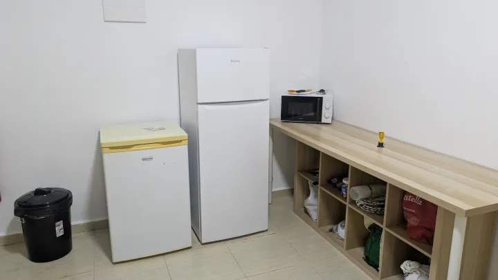 Zona de apoyo del local con frigoríficos, microondas y una encimera de madera.